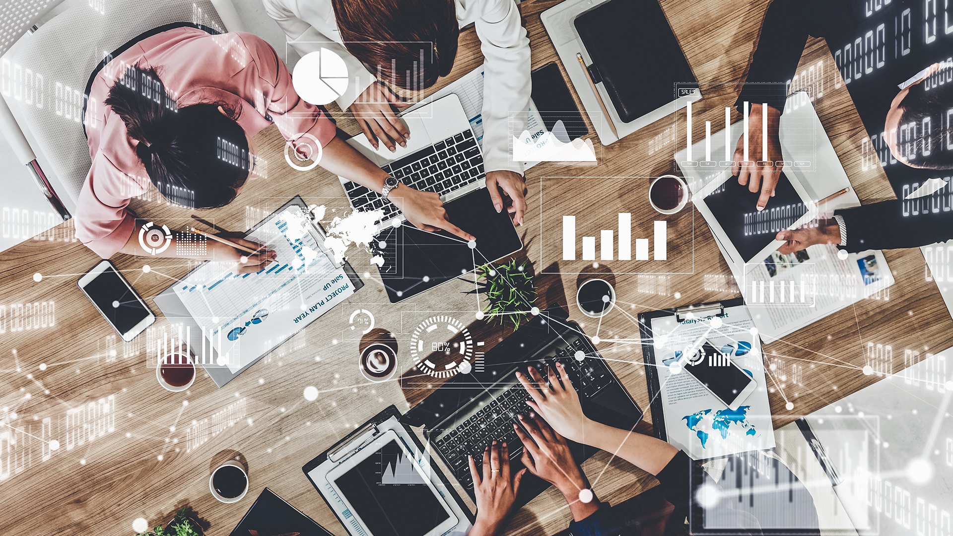 group of people working around a table with digital graphs in the foreground