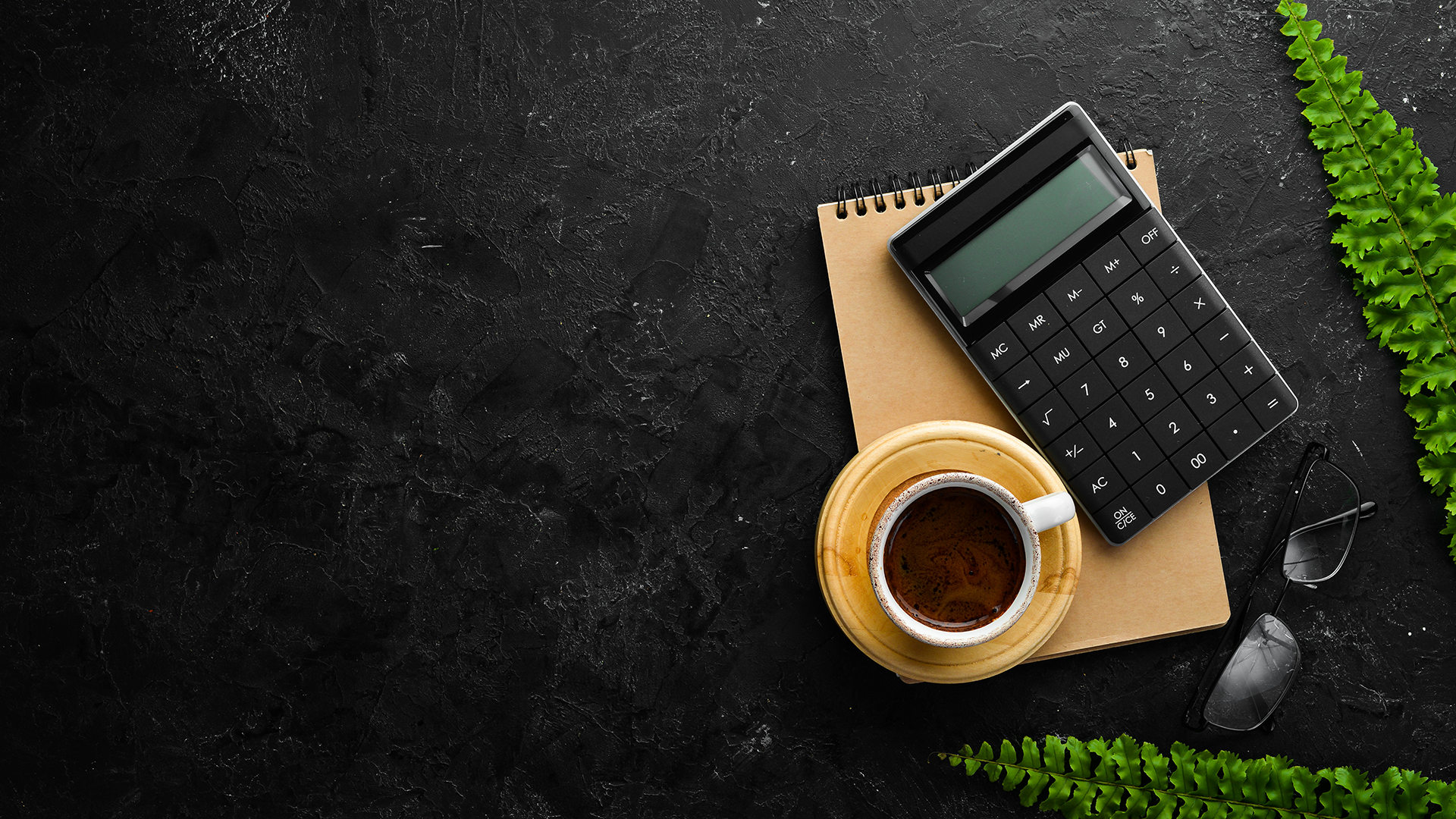 calculator, coffee, notebook, glasses, and ferns on a table