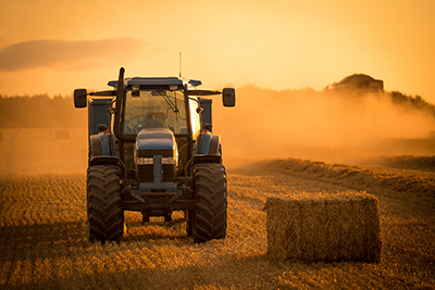 tractor in field next to a hay bale